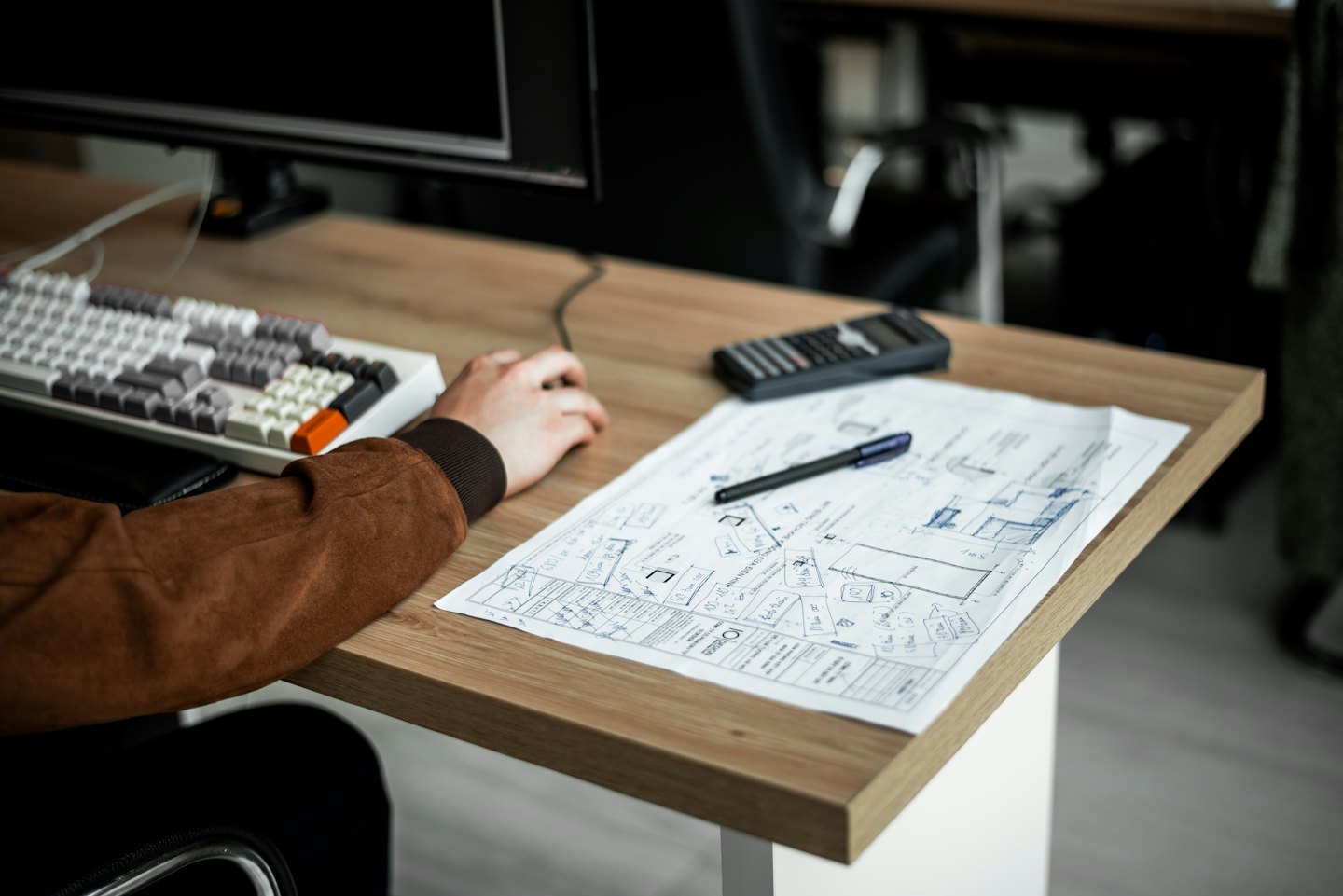 Ein Designer arbeitet an Architekturplänen und UI-Wireframes am Schreibtisch.